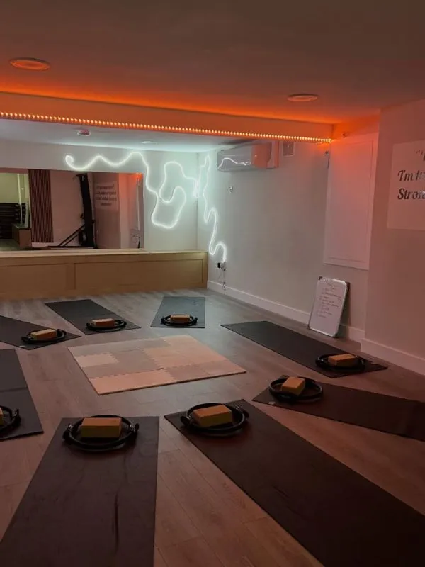 The candle-lit basement studio set up for a yoga class with mats and bolsters